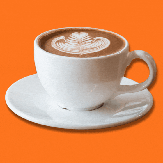 A hot latte in a white coffee mug with espresso beans falling around it. 
