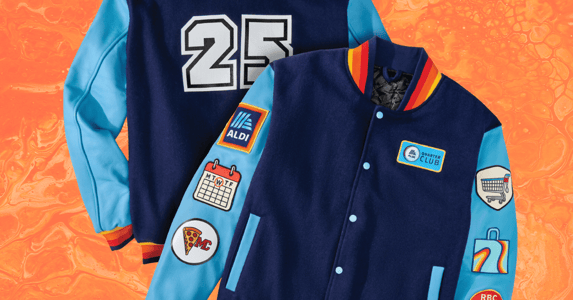A blue Aldi-branded varsity jacket with the number 25 on it. Patches feature a calendar, Aldi's logo, a spice of pizza, and a shopping cart.