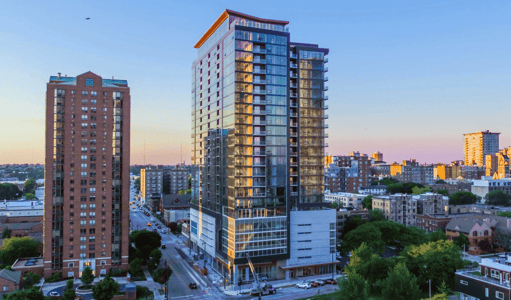 The glass-fronted exterior of a 25-story residential building.