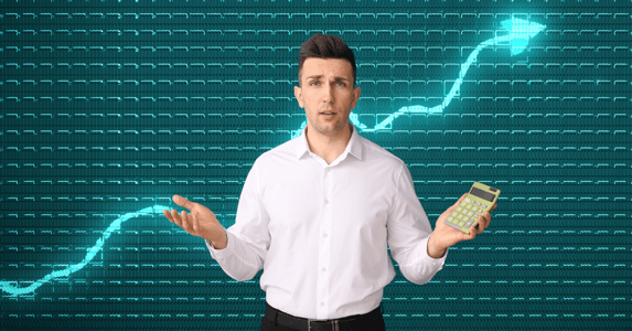 A conflicted man holds a calculator in front of a chart with a rising line.