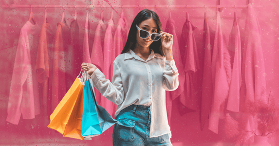 A young woman wearing large sunglasses and holding two shopping bags.