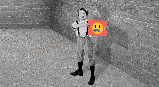 A grayscale, vintage-style photo of a young boy in overalls holding a bright red card with a cringing emoji over his face.