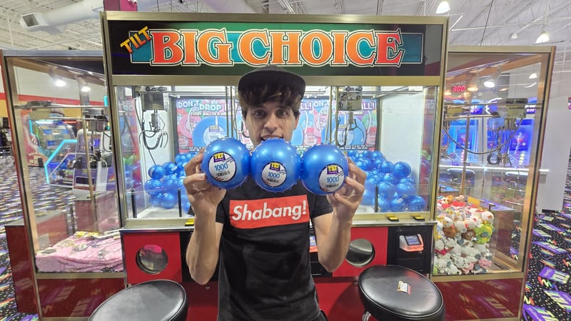 Arcade Matt: YouTuber Matt Magnone holds up three blue prize balls in front of a "BIG CHOICE" claw machine.