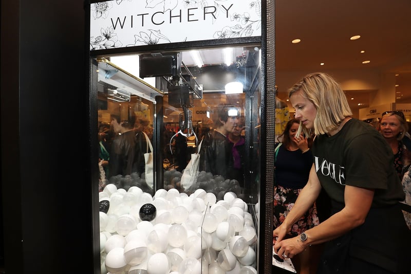 Sydney Fashion Event: A woman plays a claw machine filled with white capsules at a "WITCHERY" fashion event in Sydney.