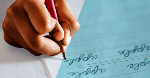 A hand holding a red pencil and writing in cursive.