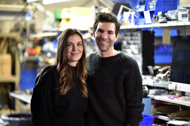 A portrait of Retrospekt founders Kori and Adam Fuerst standing together in their workshop.