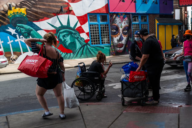 Kensington residents carrying belongings during a crackdown on a homeless encampment.