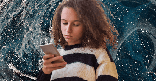 An unsmiling woman in a white-and-black striped sweater stares at her phone.