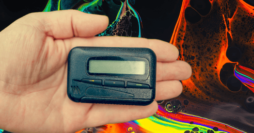 An open hand holds a black pager.