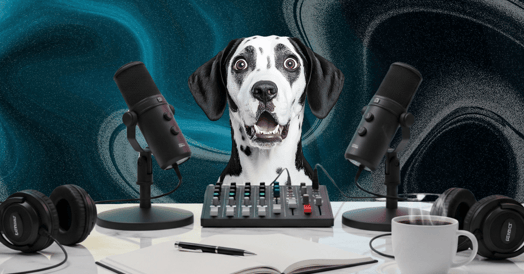A black and white dog making a shocked face behind podcasting microphones. 