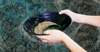 Two hands demonstrate panning for gold.