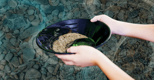 Two hands demonstrate panning for gold.