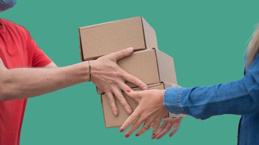 A man hands three small cardboard boxes to a woman. 