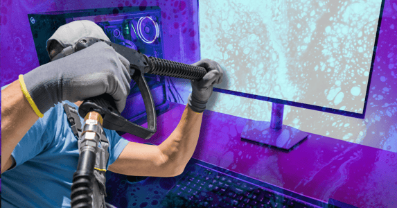 A man uses a power washer on a computer monitor.
