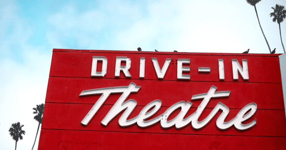 A sign that reads 'drive-in theater' flanked by palm trees. 