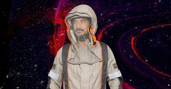 A man wearing an Electrostatics conductive suit, which looks like a tan coverall with a netted hood.
