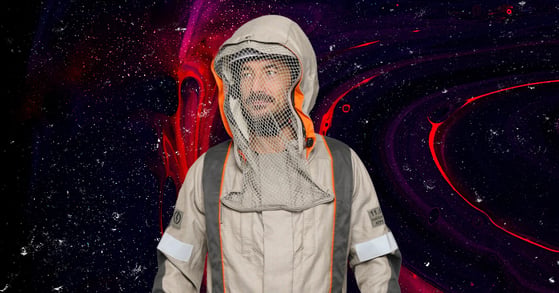 A man wearing an Electrostatics conductive suit, which looks like a tan coverall with a netted hood.