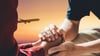 Two people hold hands while a plane flies in the background.