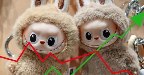 Two Labubu dolls. In front, a red decreasing arrow and a green increasing arrow.