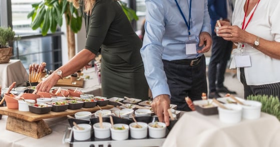Several people, visible from waist to neck, select food from a buffet.