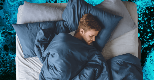 A man sleeping in bed under blue covers. 