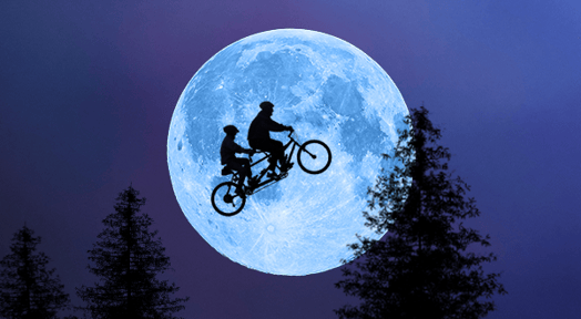A tandem bike flies through the sky, silhouetted by the moon